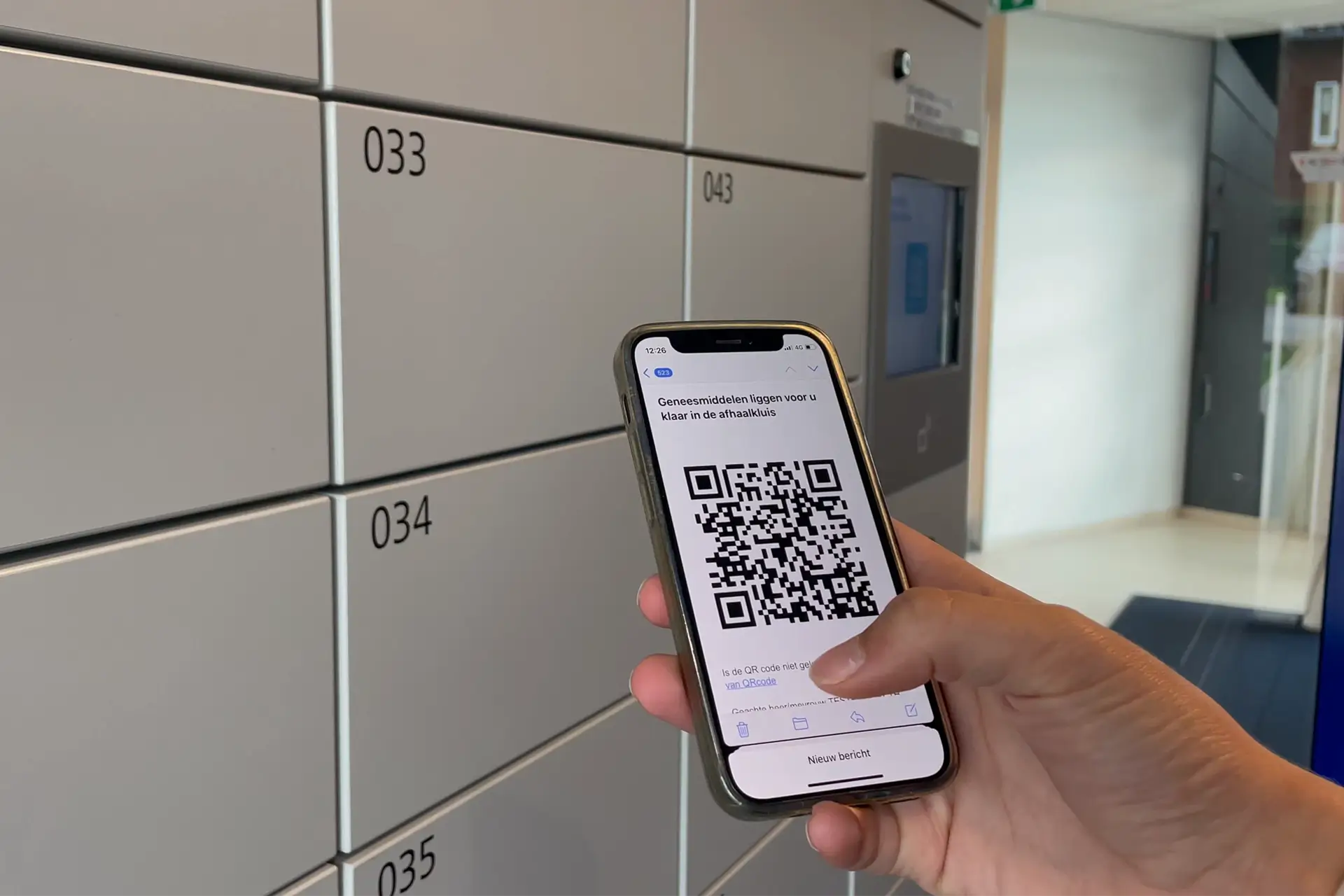 Persoon houdt smartphone met QR-code voor medicijnafhaalbericht voor een Nextlox medicijnlocker